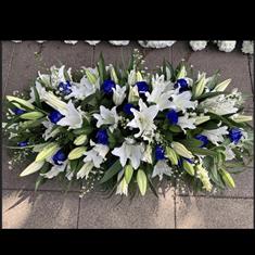 Casket spray white Lilly and blue roses 